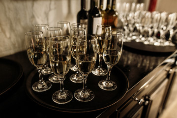luxury glasses with golden champagne on stylish decorated table at wedding reception. expensive catering at restaurant for celebrations. transparent glass and space for text. alcohol bar