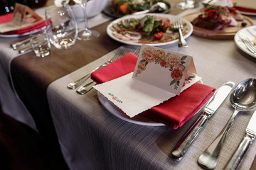 Elegant wedding reception catering, luxury table arrangement - floral greeting card on red napkin near expensive silverware close-up, fine dining concept