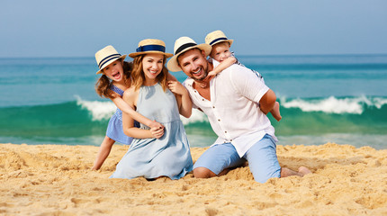 happy family father, mother and children on beach at sea