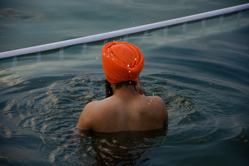 Sij de espaldas mojándose en el lago de néctar del Templo Dorado o de Oro de Amritsar o Harmandir Sahib. Sijs. La India