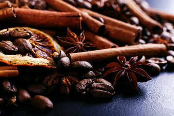 Cinnamon sticks, star anise, coffee beans and dried orange on the kitchen table. Fragrant spices for coffee drink, close-up.