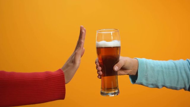 Female rejecting beer glass showing stop gesture, bad habit refusal, health care