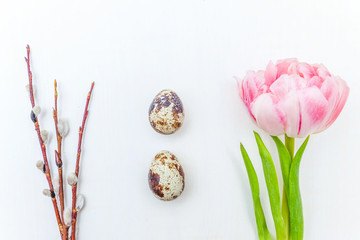 Spring greeting card. Easter eggs cotton willow branch and pink fresh tulip flowers bouquet on rustic white wooden background. Easter concept. Flat lay top view copy space. Spring flowers tulips