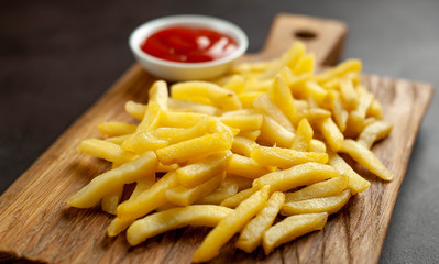 French fries with ketchup on a cutting board, background is concrete