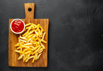 French fries with ketchup on a cutting board, background is concrete
