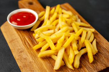French fries with ketchup on a cutting board, background is concrete