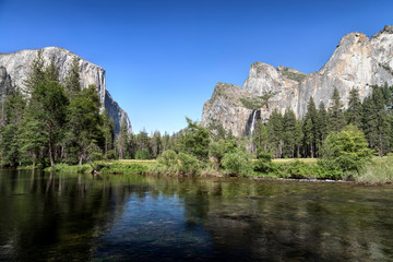 Fototapeta na wymiar Iconic features of the amazingly beautiful Yosemite Valley are viewed from the bank of California’s Merced River.