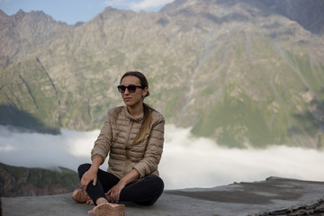 Young beautiful girl in a jacket with sunglasses against the background of the Caucasus Mountains in Georgia. Close-up