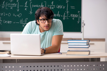 Young male student mathematician in front of chalkboard 