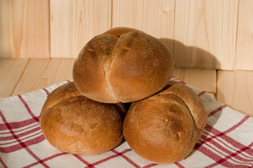 Three buns of wheat flour on a white towel with red stripes. Belgian bread. Closeup