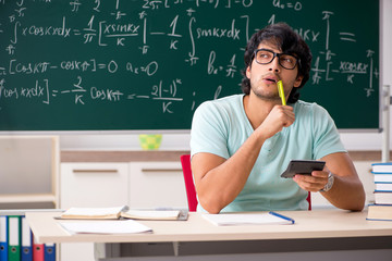 Young male student mathematician in front of chalkboard 
