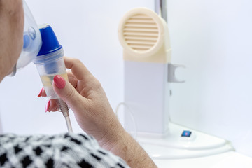A female hand closes the lips and nose with an inhaler mask to breathe the medicated vapor. Inhalation procedure. Equipment in the hospital. Treatment of the respiratory tract and pulmonary system.