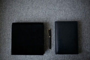 book with pen and notebook on gray background