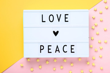Lightbox with words Love Peace with paper stars on colorful background