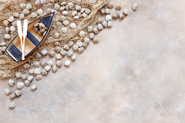 Fresh raw Surf clam chamelea gallina,  fishing boat with oars and  fishnet. Top view, close up on sand concrete background