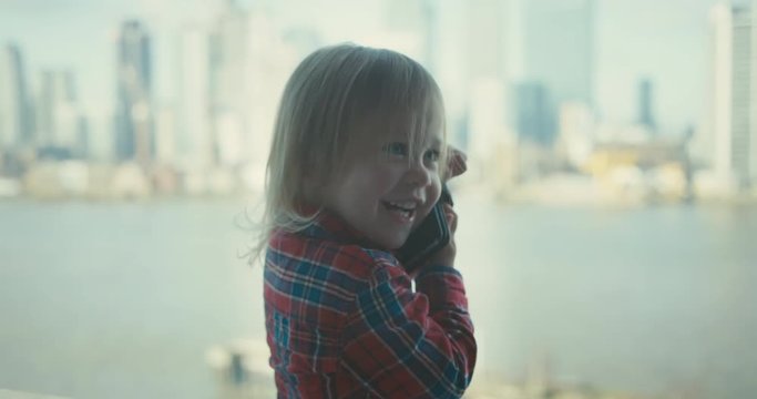Little toddler talking on the phone in the city