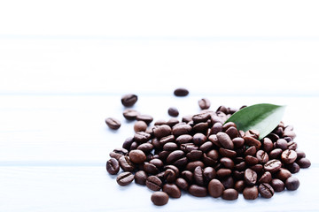 Coffee beans with green leaf on wooden table