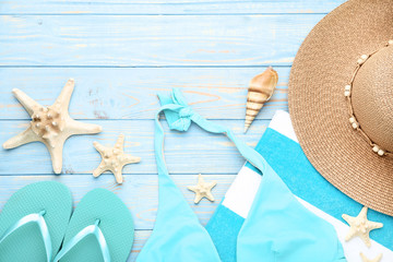 Swimsuit with seashells and flip flops on wooden table