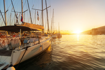 Sailing yachts parked in harbour in sunset light.