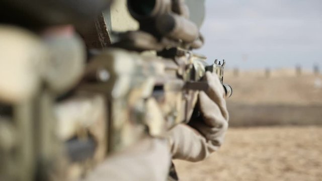 Major`s hands firing from automated rifle with flying off cartridges in slo-mo   