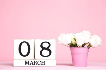 Women's Day on wooden calendar with eustoma flowers in pink bucket
