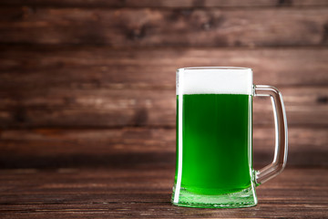 St. Patrick's Day. Glass mug with green beer on brown wooden background