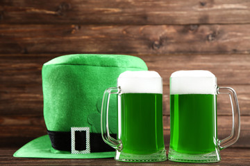 St. Patrick's Day. Green beer in mugs with hat on wooden background