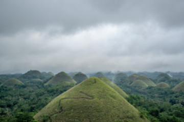 Main landmark of Bohol Island in Philippines - Chocolate Hills in overcast weather, blurred view