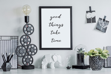 Stylish black and white home decor mock up. Creative desk with blank picture frame or poster, desk objects, office supplies, photos, elephant figure and plants in design pots on a white background.