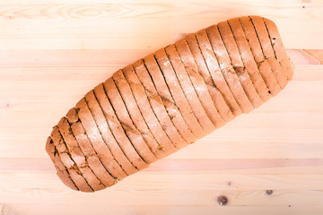 Sliced loaf of bread on wooden background, top view