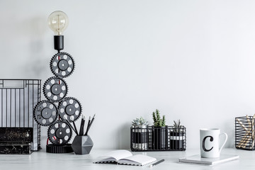 Modern and stylish black and white home decor. Creative desk with copy space or inscription, desk objects, office supplies, books, cup of coffee, succulent and design table lamp on a white background.