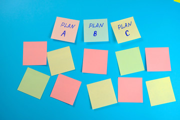  Many colored empty office stickers on a blue background and three separately with plan A plfn B and plan C . Mock-up