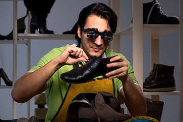 Young shoemaker in workshop at night 