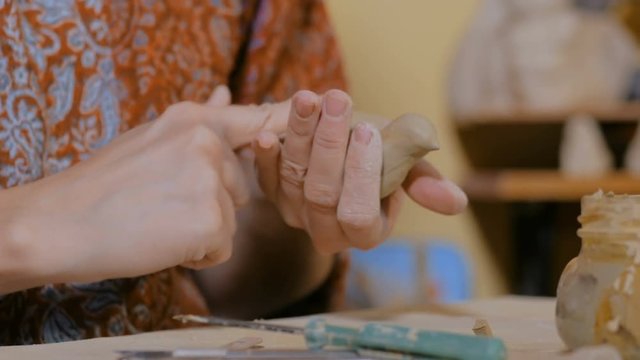 Professional woman potter making ceramic souvenir penny whistle toy bird in pottery workshop, studio. Crafting, artwork and handmade concept