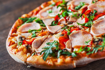 Pizza with Mozzarella cheese, mushrooms, ham, tomato sauce, pepper, Spices and Fresh arugula. Italian pizza on wooden table background
