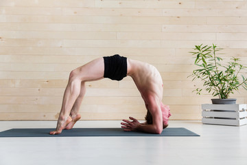 Sporty man practicing yoga on yoga class, bridgepose