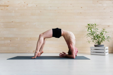 Sporty man practicing yoga on yoga class, bridgepose