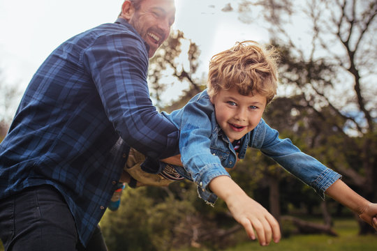 Little boy flying in arms of his dad