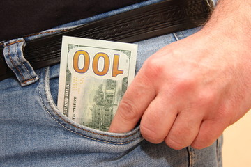One hundred dollars in men's blue jeans pocket with hand - walking-around money