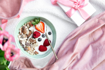 Start the day the healthy way. Granola, yogurt and berries in a beautiful green rustic plate with copy space