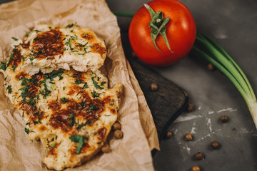 Chicken chop meat under cheese on a gray background tomatoes pepper tree