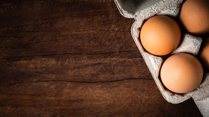 Fresh brown eggs in a carton box was placed on a wooden table to prepare food. Have copyspace to...