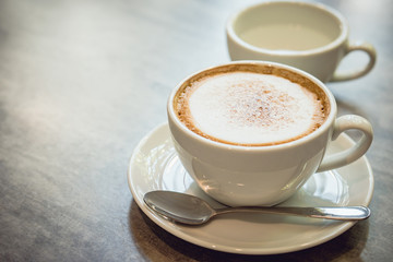 Hot coffee and hot tea place on the marble table in early morning with copyspace, white cup and silver spoon.