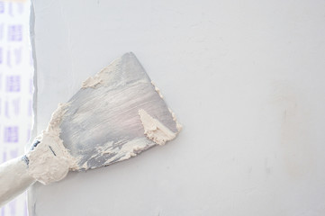 Spatula with putty. The process of applying the paste on the wall