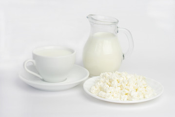 Cup of milk, jug of milk and cottage cheese on a white background