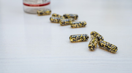 Scattered capsules on a white, wooden background