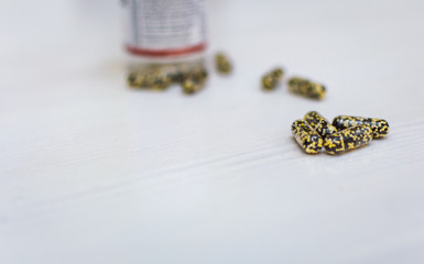 Scattered capsules on a white, wooden background