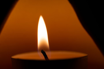 Underexposed low light photo of candle in aromatic lamp. Close-up view