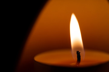 Underexposed low light photo of candle in aromatic lamp. Close-up view