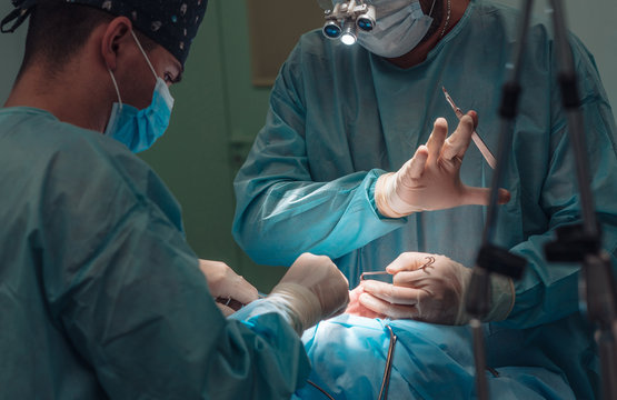 Surgeon and his assistant performing cosmetic surgery on nose